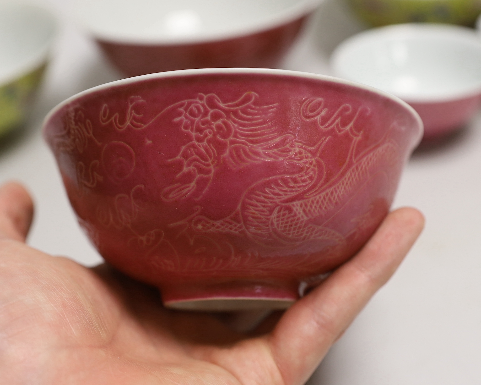 Five Chinese pink monochrome bowls decorated with dragons chasing the flaming pearl together with a yellow ground pair, largest 16cm in diameter